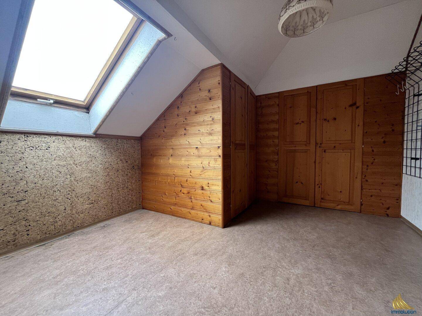 Dachgeschosszimmer mit Holzverkleidung, Einbauschränken und Dachfenster.