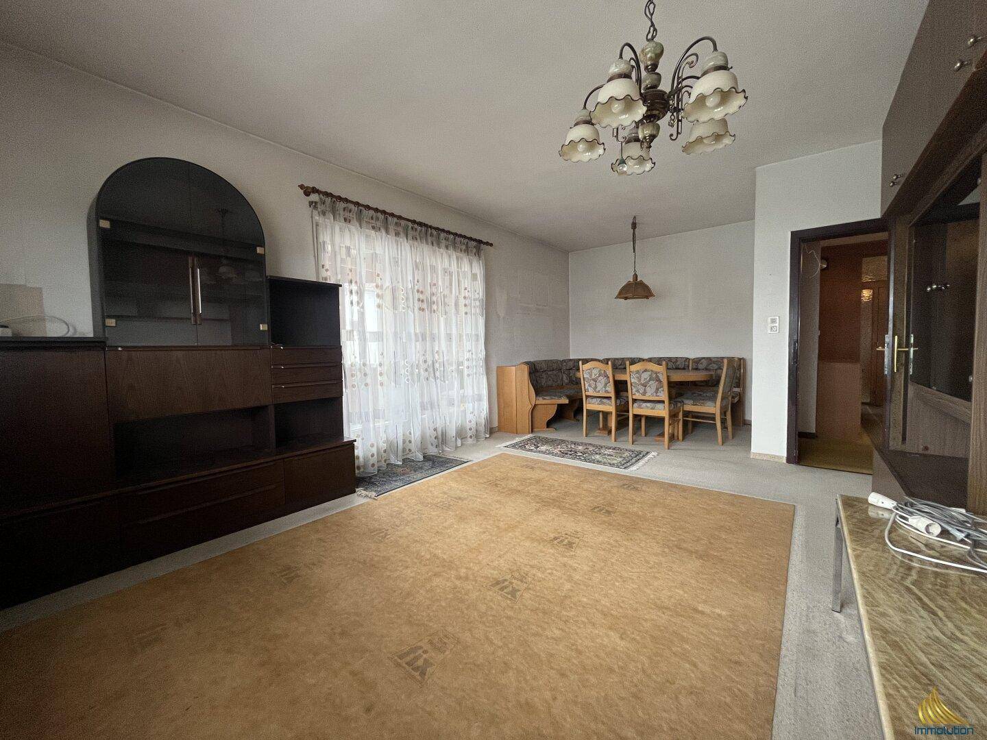 Geräumiger Wohn-Essbereich mit großem Teppich, Esstisch und Schrankwand.
