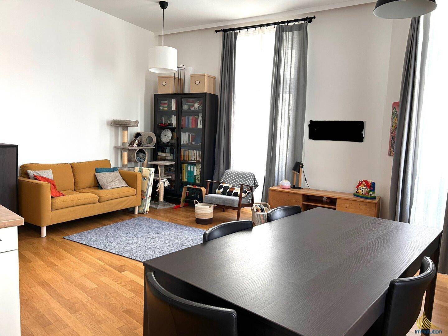 Geräumiger Wohn-Essbereich mit Holzboden, gelbem Sofa und großem Esstisch.