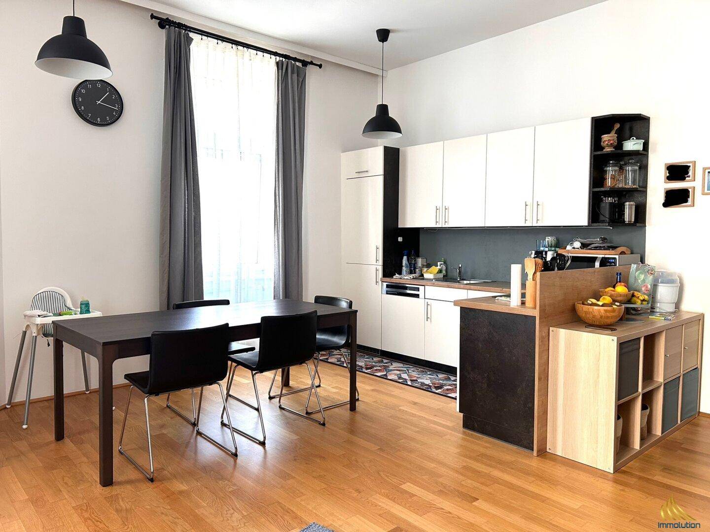 Offene Küche mit weißen Schränken, Esstisch und Holzboden im Wohnbereich integriert.