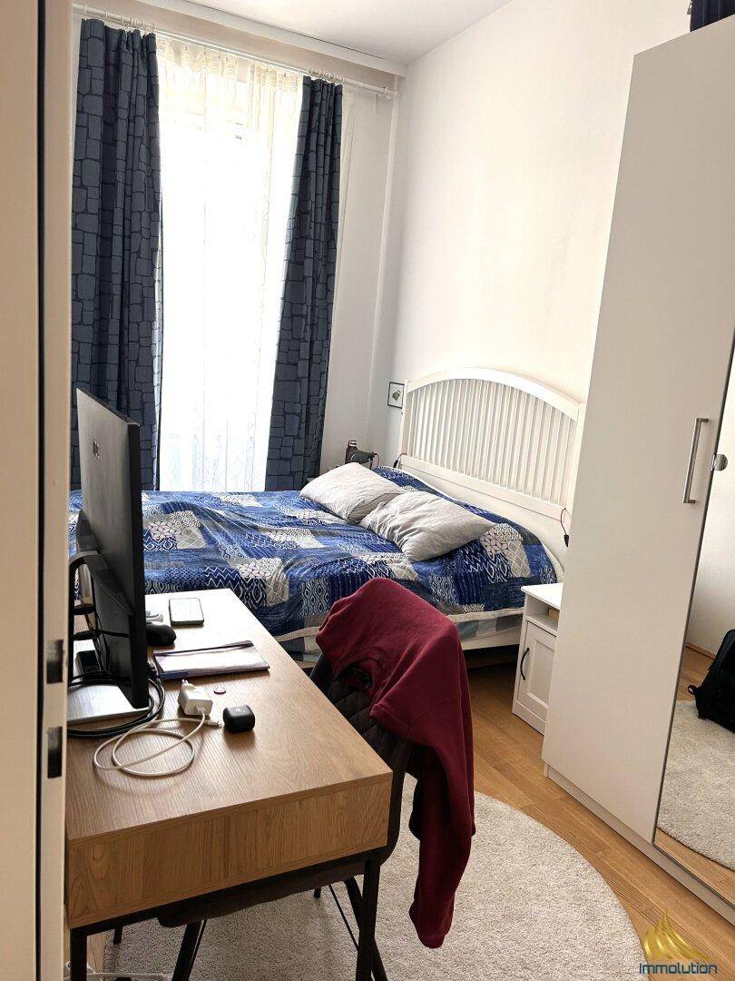 Schlafzimmer mit Holzboden, Doppelbett und einem Schreibtisch am Fenster.