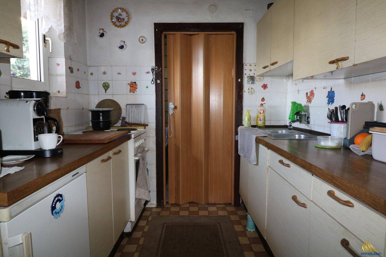 Kleine Küche mit älteren Einbauschränken, Holztheke und Fliesenboden im Landhausstil.