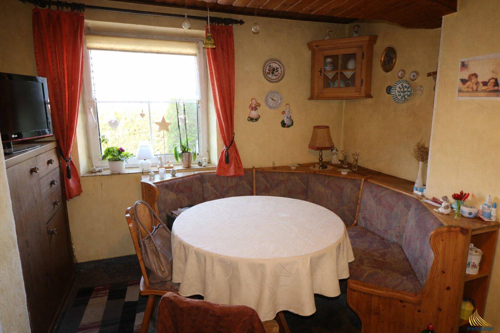 Gemütliche Essecke mit Eckbank, Holztisch und Blick ins Grüne durch das Fenster.
