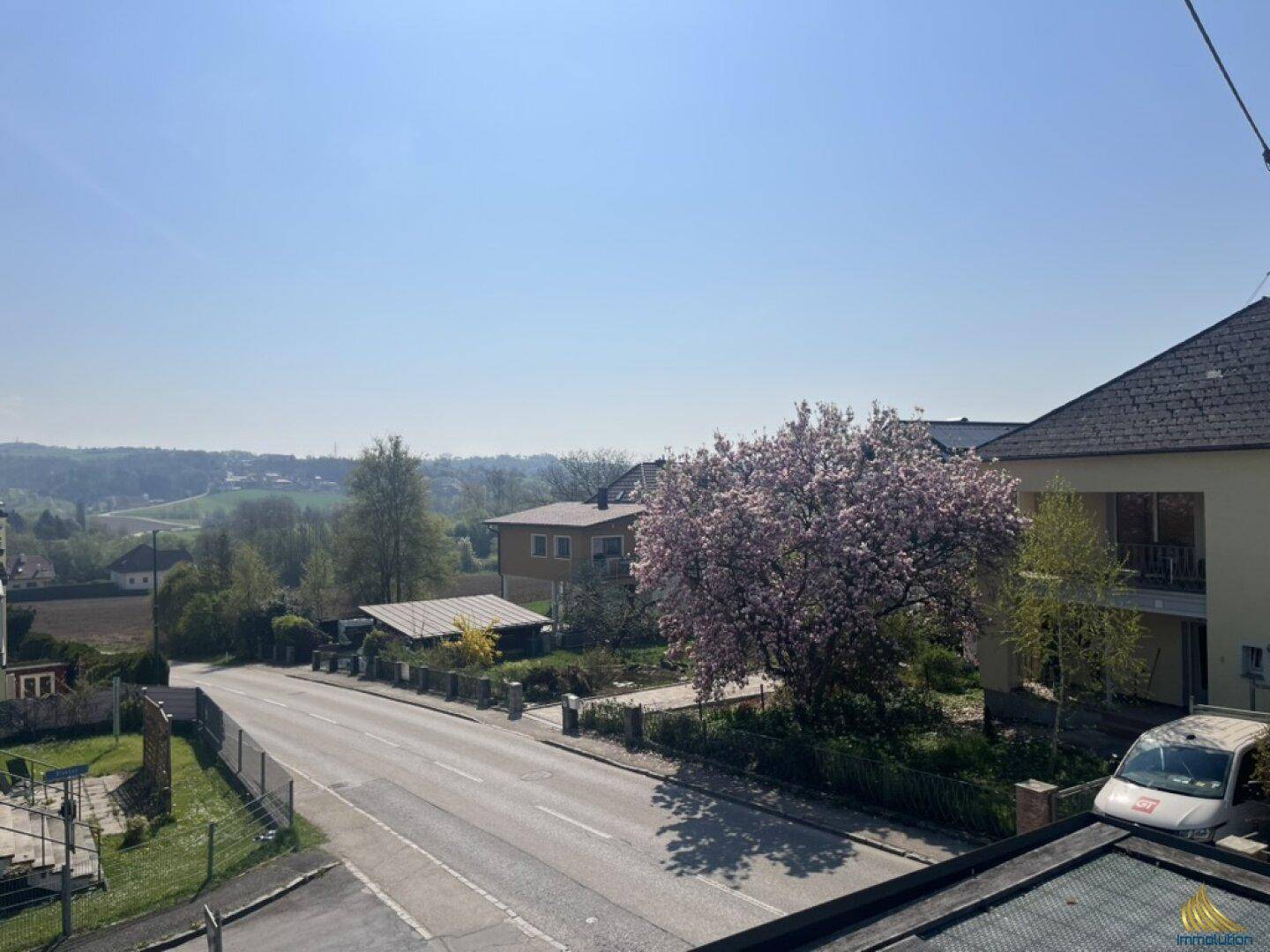 Weitläufiger Blick über die grüne Landschaft und die umliegenden Häuser an einem sonnigen Tag.
