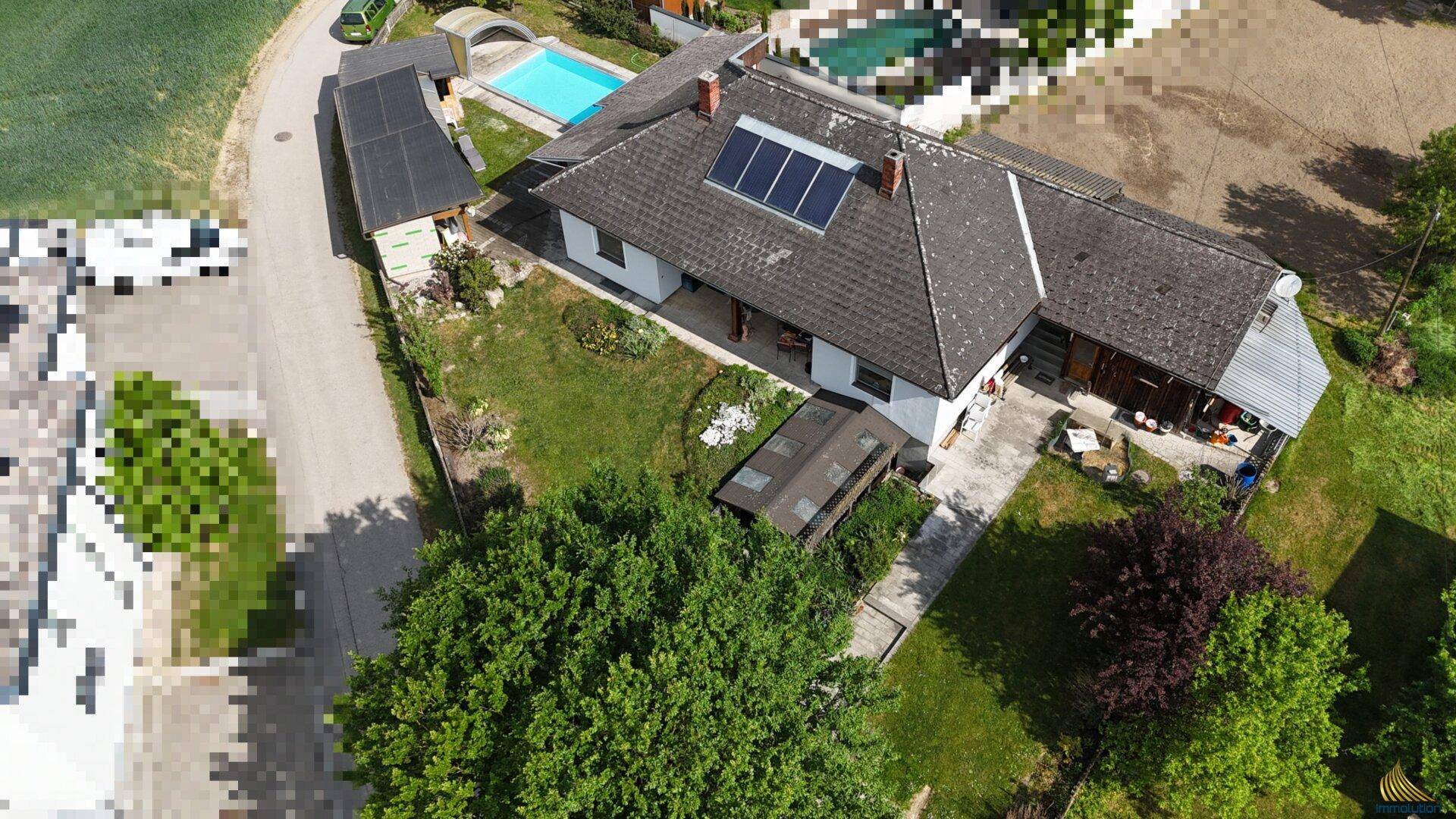 Vogelperspektive des Anwesens mit Schwimmbad, gepflegtem Garten und Solaranlage auf dem Dach.