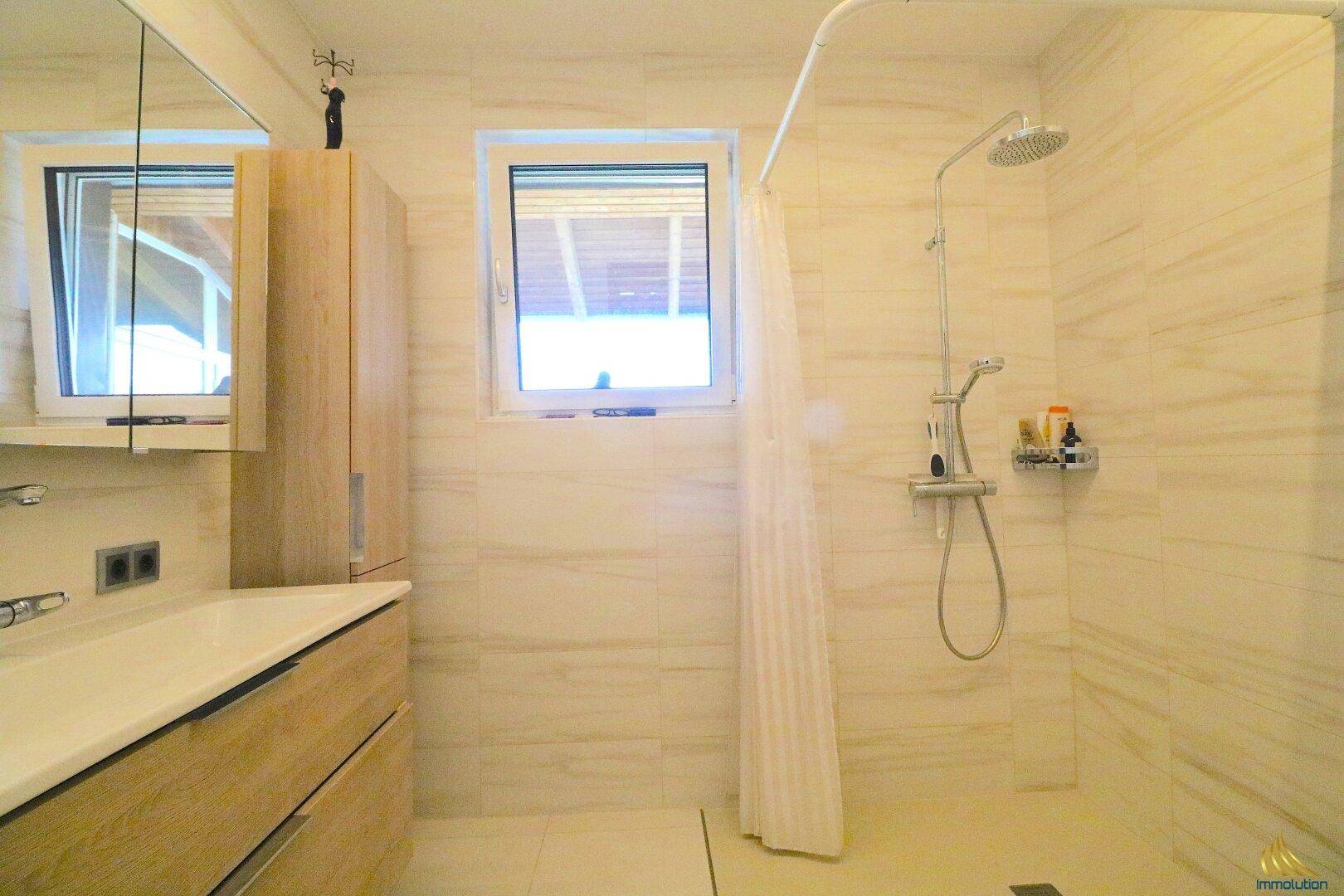 Helles Badezimmer mit ebenerdiger Dusche und Fenster für natürliche Belüftung.