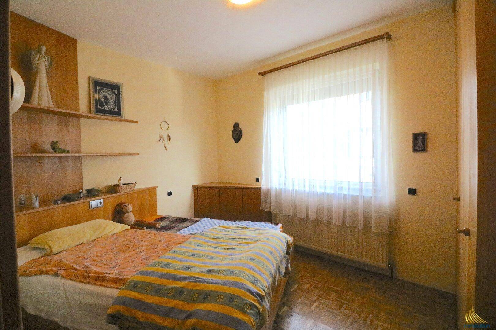 Gemütliches Schlafzimmer mit Doppelbett, Holzmöbeln und großem Fenster.