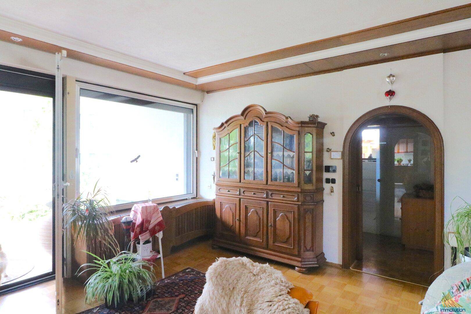 Geräumiges Wohnzimmer mit Holzboden, großem Schrank und traditionellem Bogen.