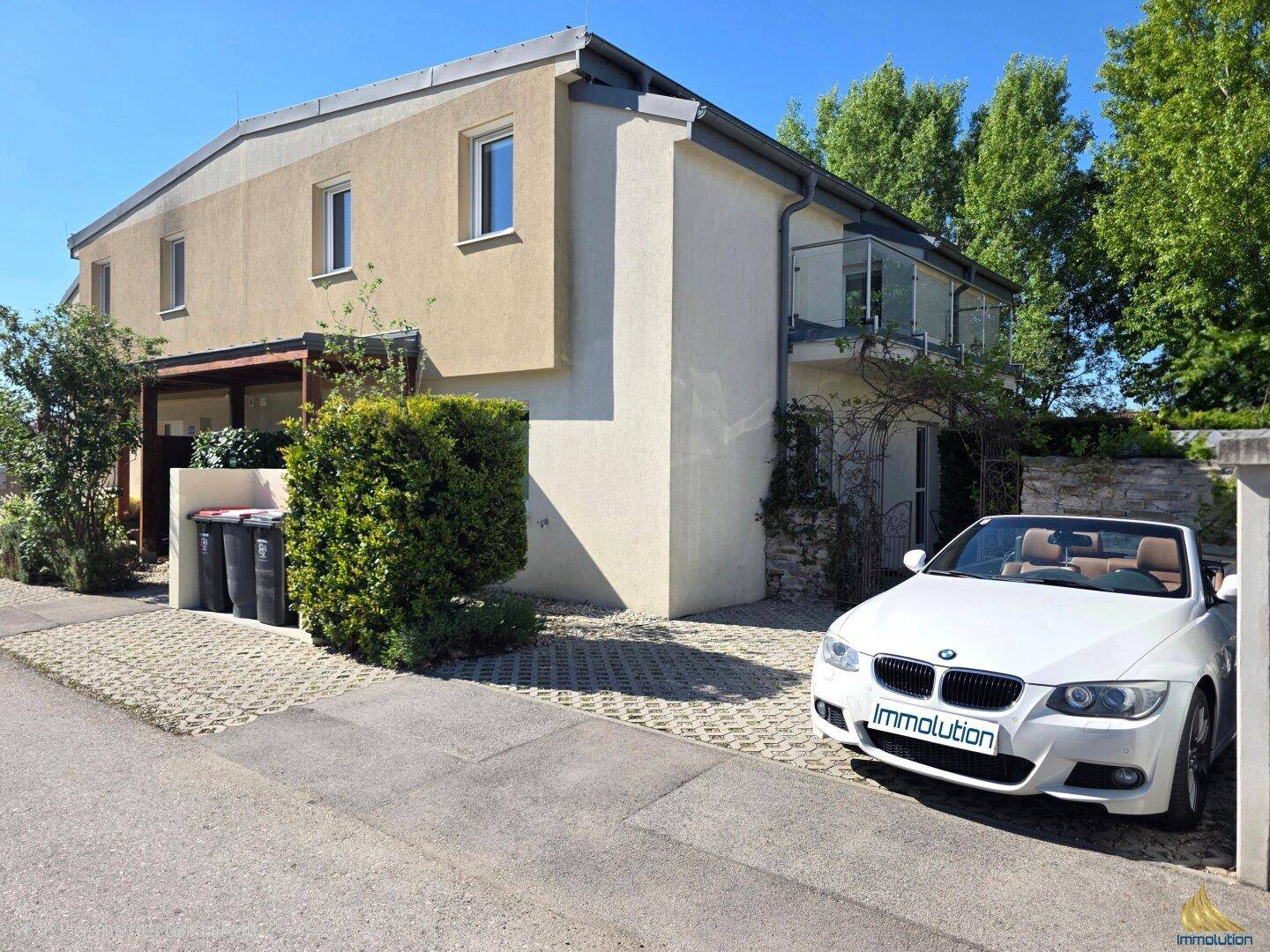 Vorderansicht des modernen Hauses mit Einfahrt und parkendem Auto.