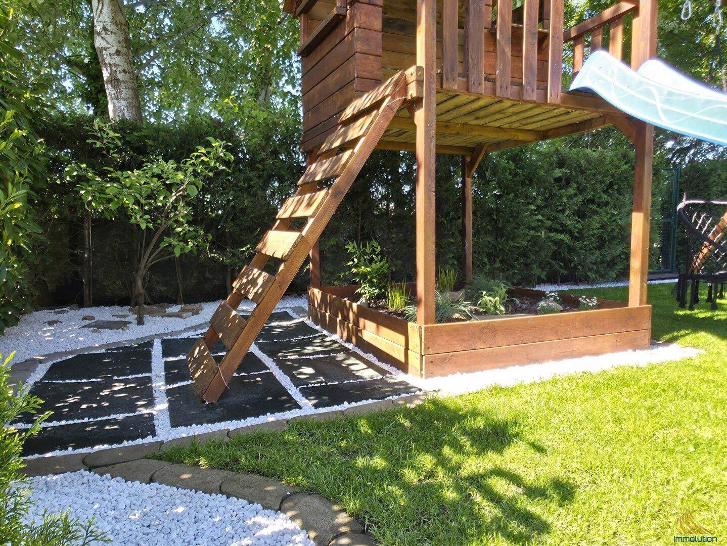Detailansicht des Spielplatzes im Garten mit Rutsche und Baumhaus.