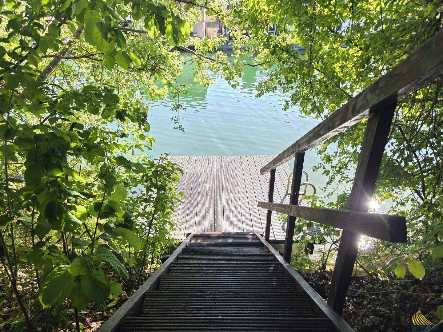 Holztreppe führt hinunter zu einem privaten Steg am klaren Seeufer.
