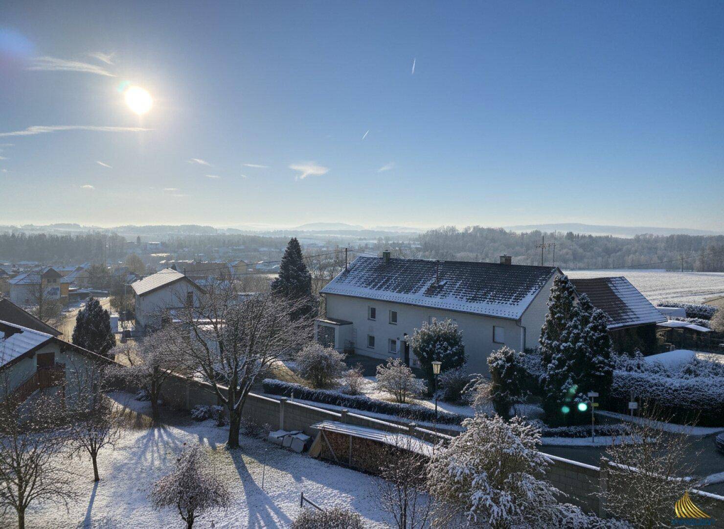 Sonniger Wintertag mit weitem Blick über eine verschneite Wohnsiedlung und die umliegende Landschaft.