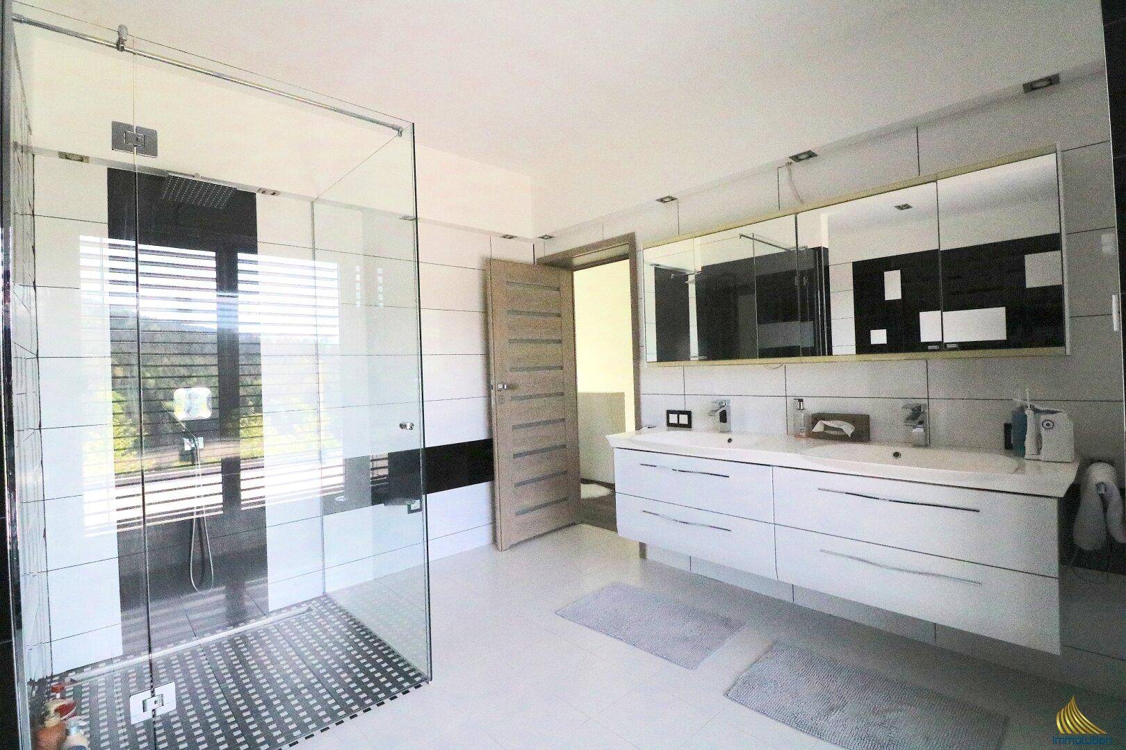 Geräumiges Badezimmer mit begehbarer Dusche, Doppelwaschbecken und eleganten Fliesen in Schwarz-Weiß.