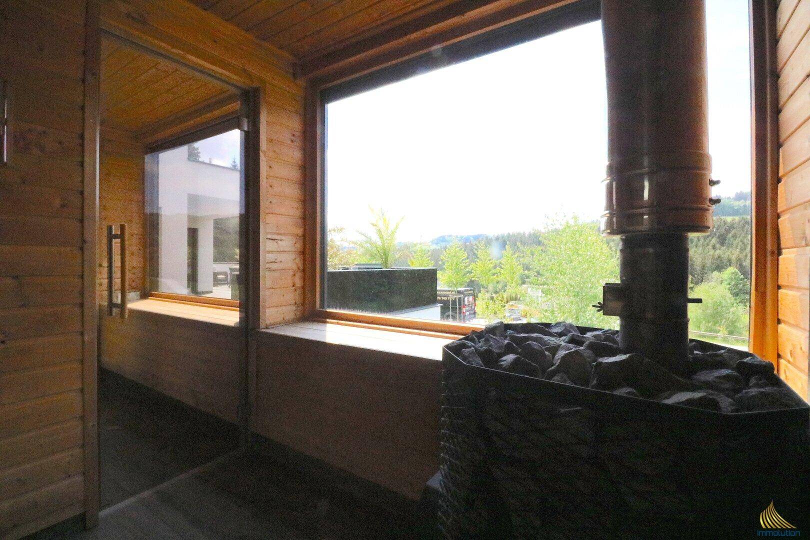 Moderne Sauna mit Holzverkleidung, Saunaofen und großem Fenster mit Panoramablick.