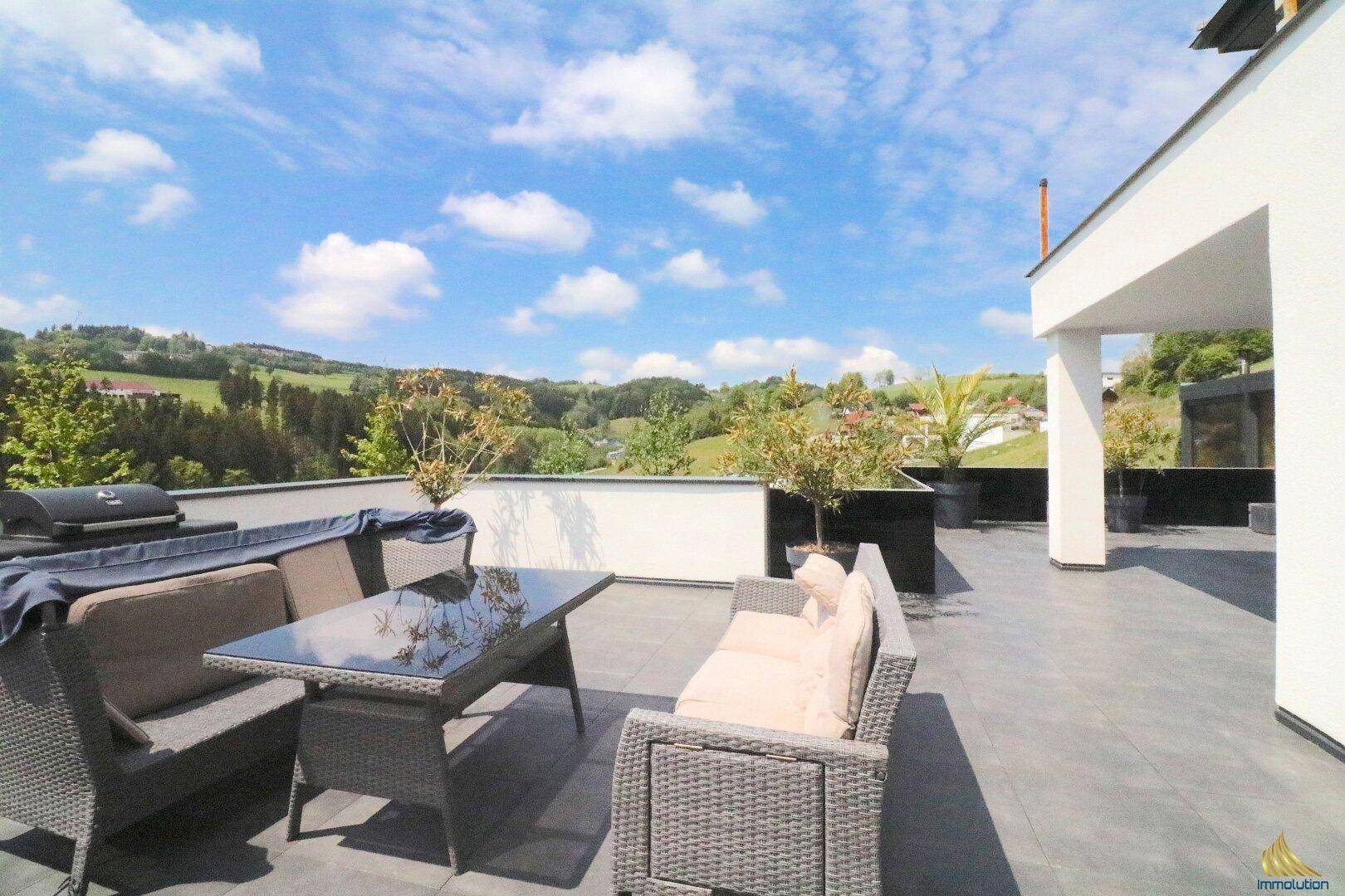 Geräumige Terrasse mit bequemen Outdoor-Möbeln und einem atemberaubenden Panoramablick ins Grüne.