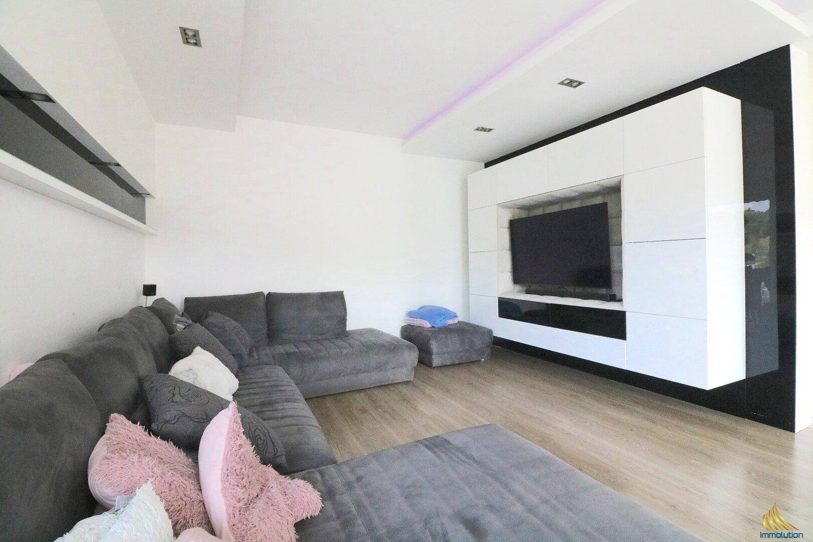 Geräumiges Wohnzimmer mit großem Ecksofa, modernem TV-Möbel und hellem Laminatboden.