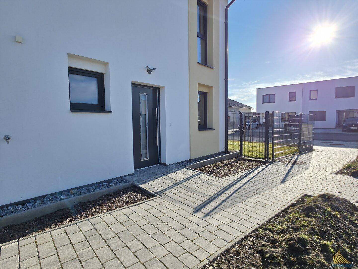 Eingangsbereich des Neubaus mit gepflastertem Weg und modernem Haustürdesign.