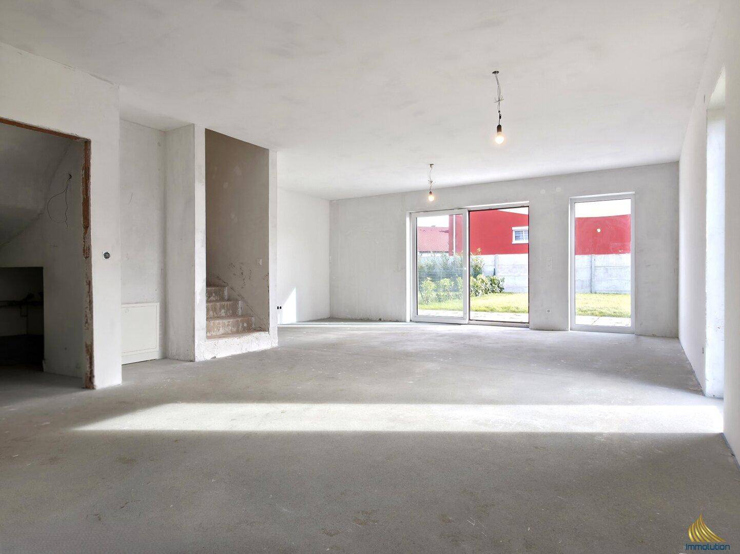 Geräumiger Rohbau-Wohnbereich mit großer Schiebetür zum Garten und viel Tageslicht.