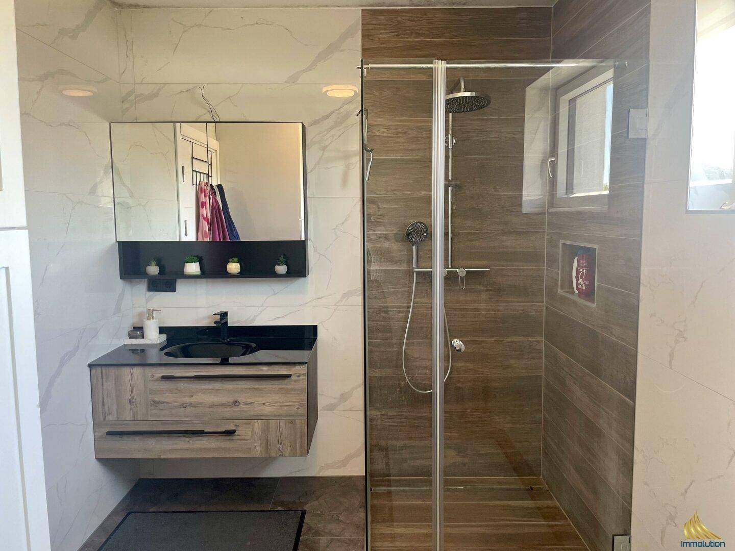 Modernes Badezimmer mit begehbarer Dusche, stilvollem Waschtisch und Marmorfliesen.