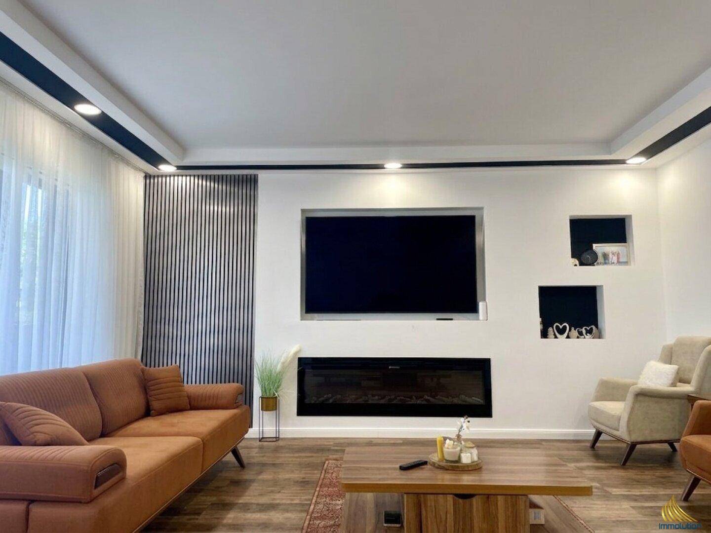 Geräumiges Wohnzimmer mit modernem Design, großem Sofa und integriertem Elektrokamin.