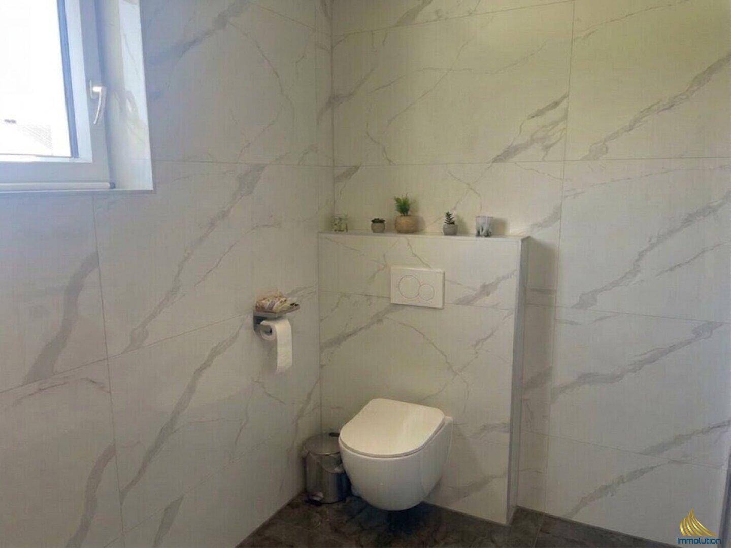 Modernes Gäste-WC mit wandhängender Toilette und großformatigen Marmorfliesen.