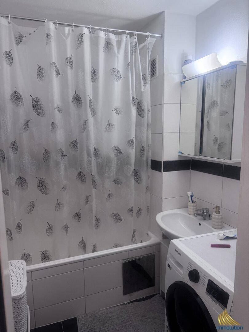 Funktionales Badezimmer mit Badewanne, Duschvorhang, Waschbecken und Waschmaschine.