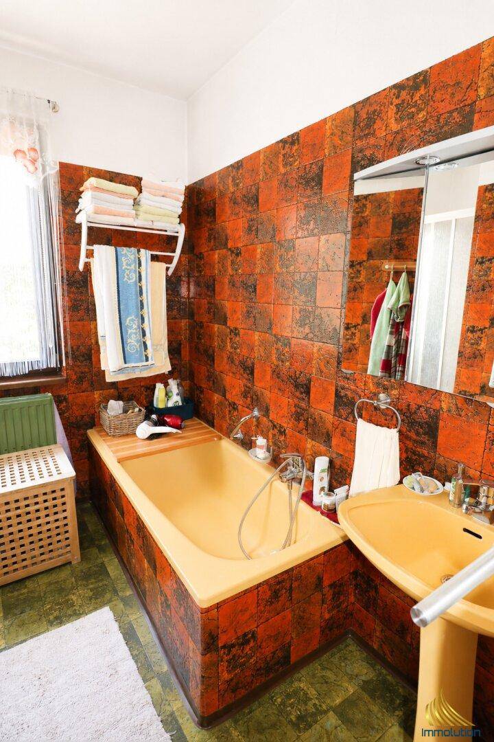 Badezimmer im Stil der 80er Jahre mit orange-schwarzen Fliesen und gelber Badewanne.