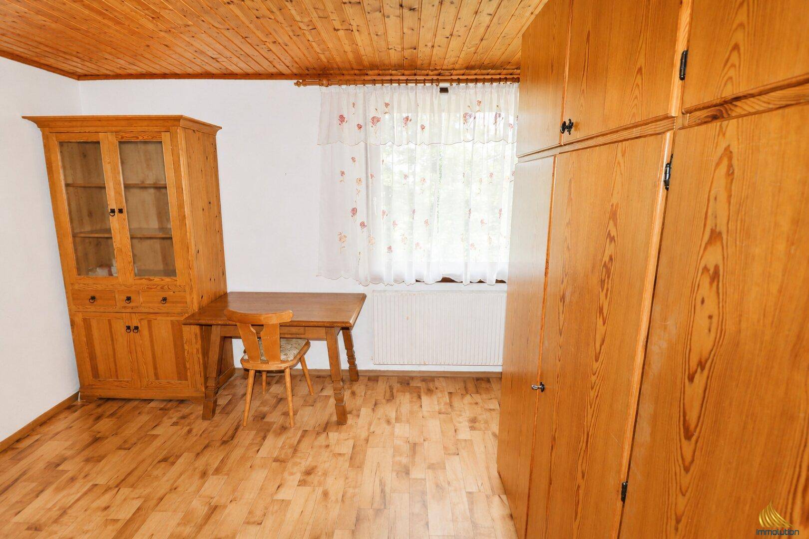 Geräumiges Zimmer mit Holzdecke, Einbauschränken und Schreibtischbereich.