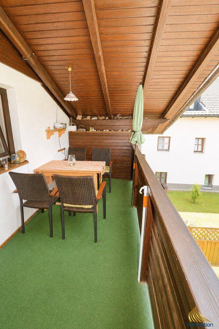 Überdachter Balkon mit Sitzgelegenheiten und Blick auf die Umgebung.