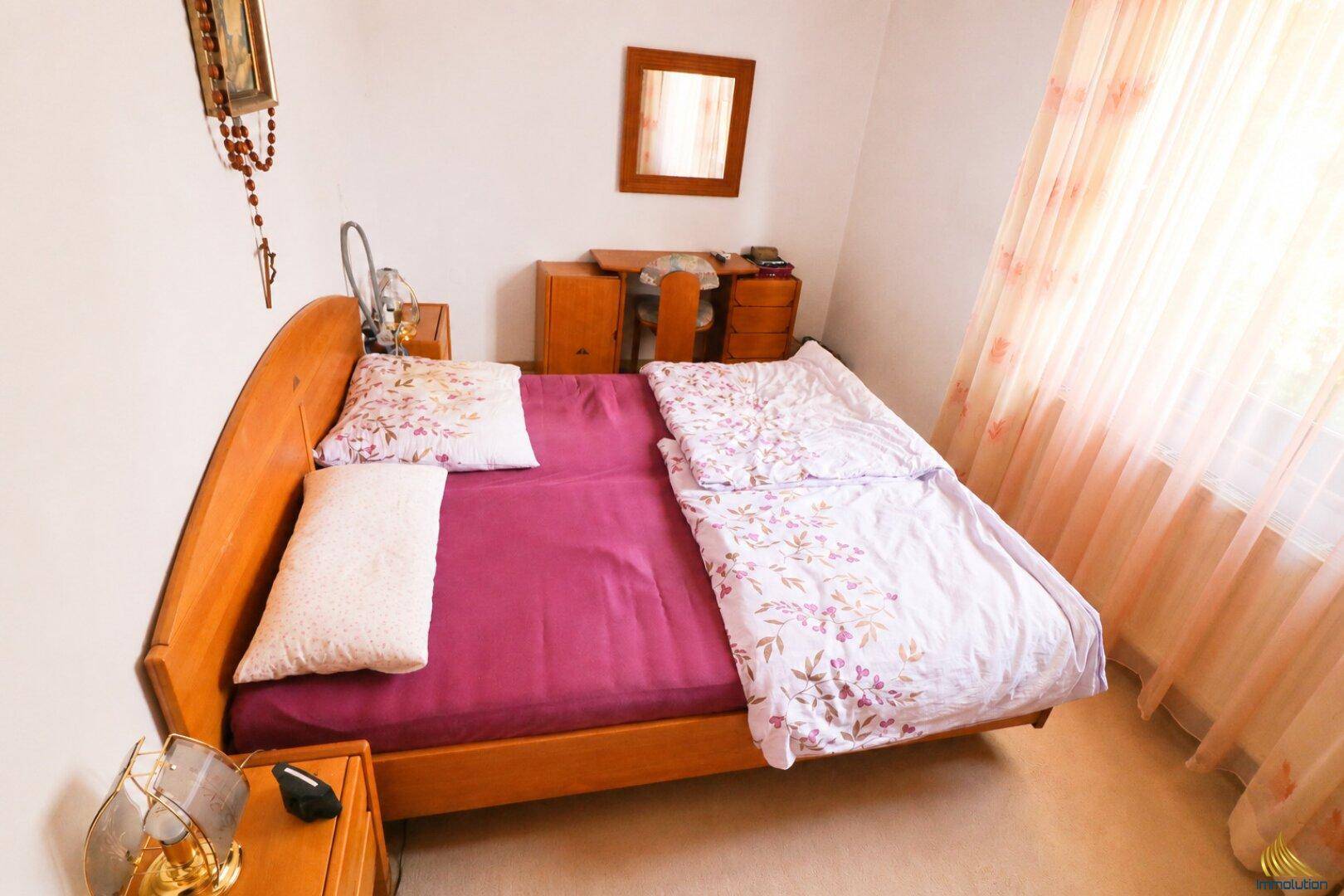 Helles Schlafzimmer mit Holzbett, Nachttischen und viel natürlichem Licht.