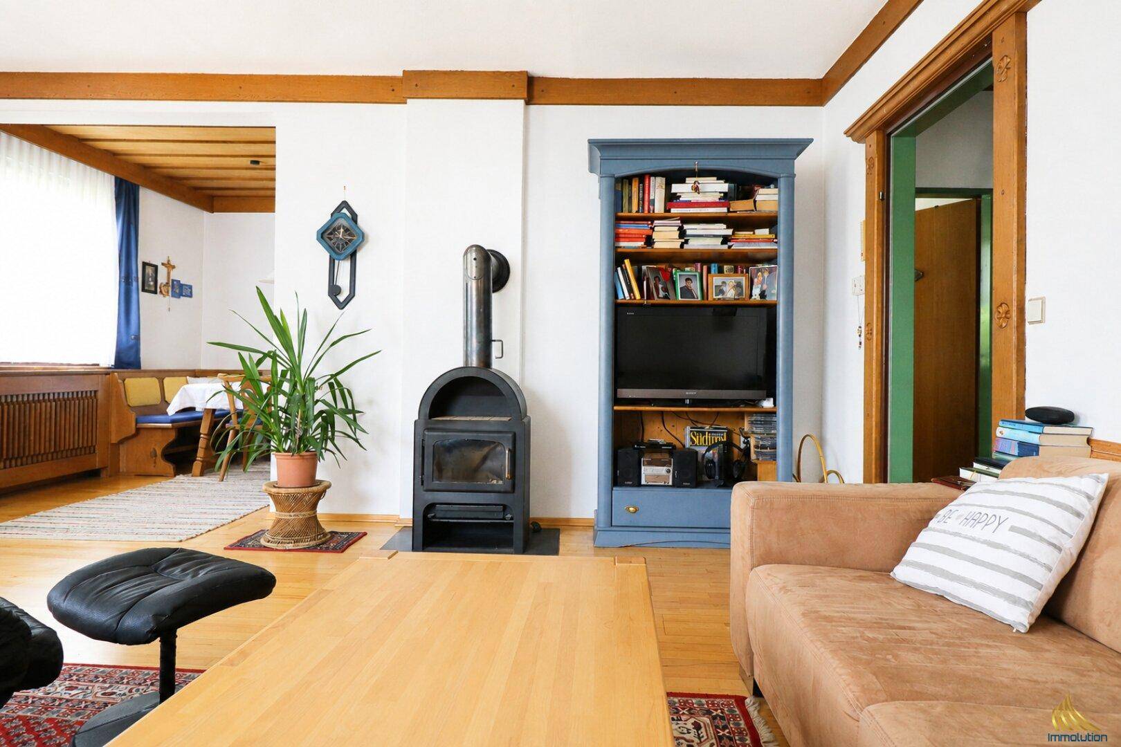 Heller Wohnbereich mit Kaminofen, bequemer Couch und Bücherregal in traditionellem Stil.