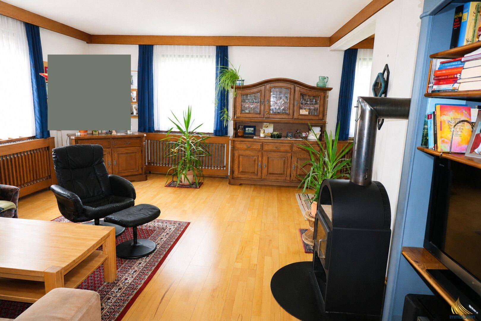 Gemütliches Wohnzimmer mit Holzofen, Parkettboden und traditionellen Holzmöbeln.