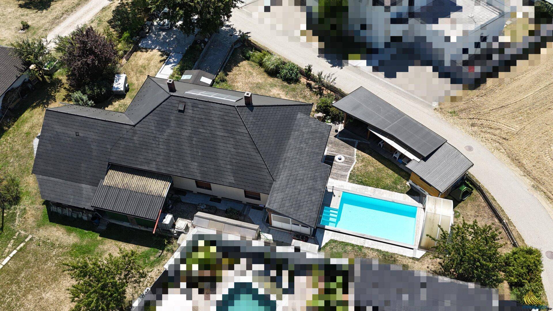 Weitläufige Ansicht des Grundstücks von oben mit Wohnhaus, Pool und angrenzenden Feldern.