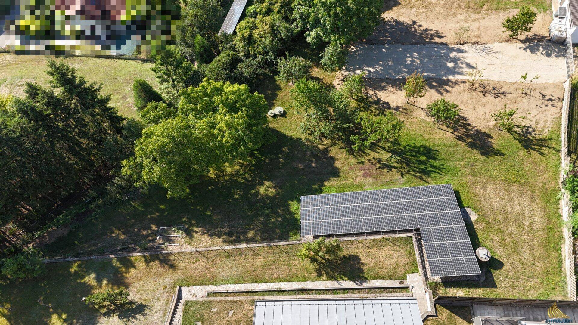 Übersicht über ein Grundstück mit Photovoltaikanlage und angrenzenden Grünflächen und Bäumen.