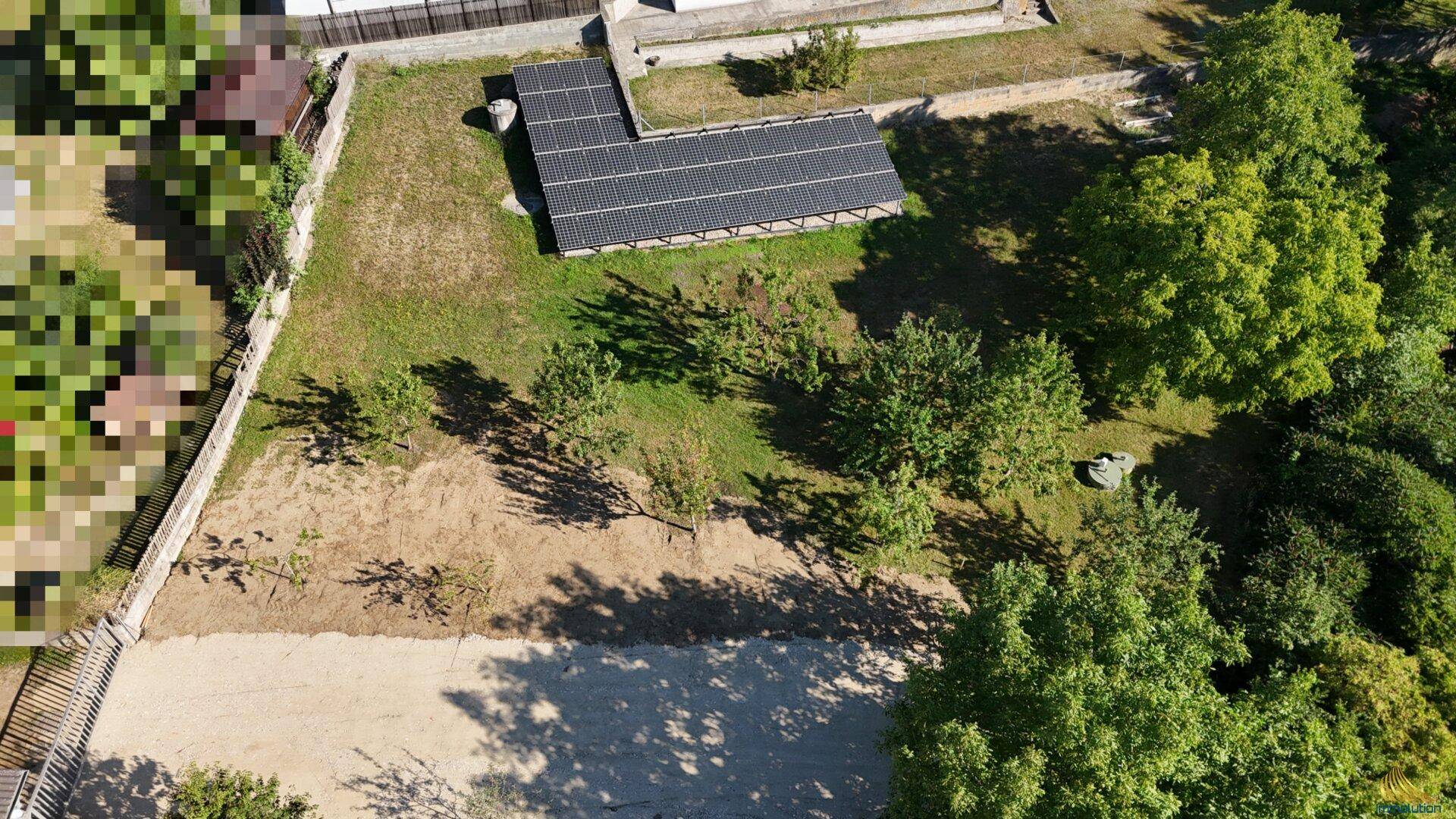 Grundstück aus der Vogelperspektive mit Solarmodulen und teilweise bewachsenem Boden.