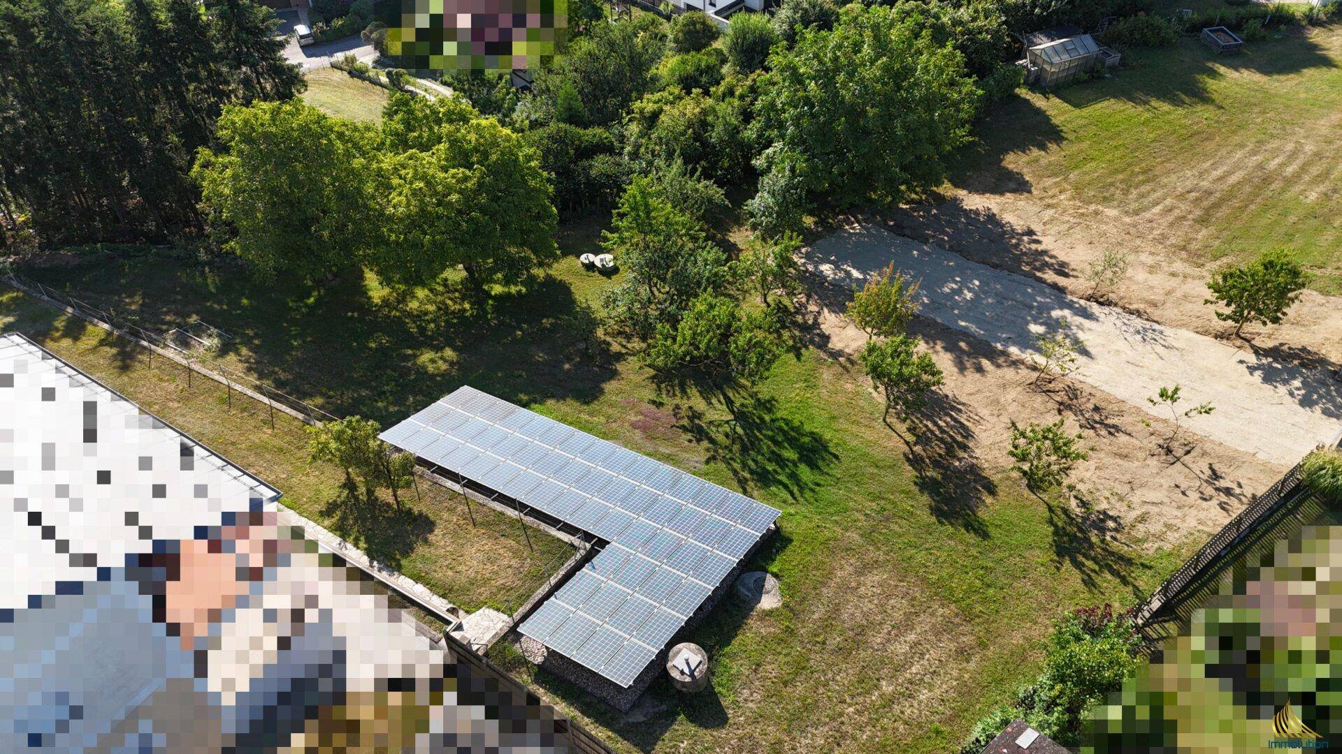 Luftbild eines Grundstücks mit Solaranlage und angrenzenden Feldern und Bäumen.