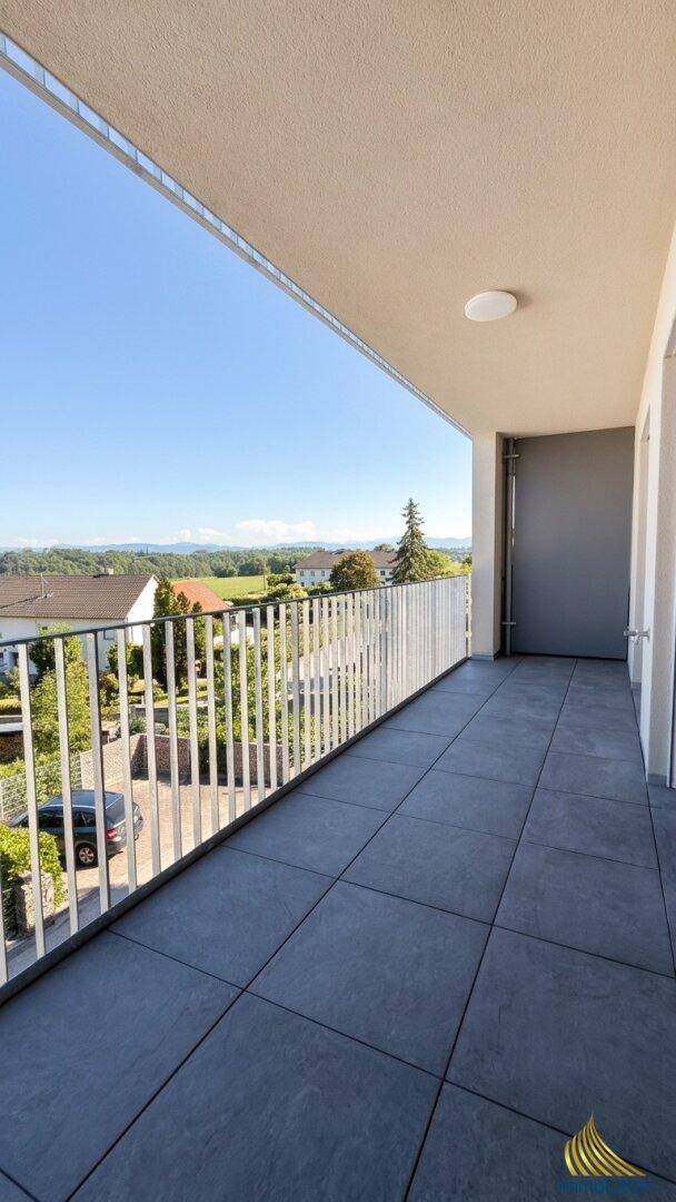 Langer Balkon mit Fliesenboden und weitem Blick über die Landschaft und grüne Felder.