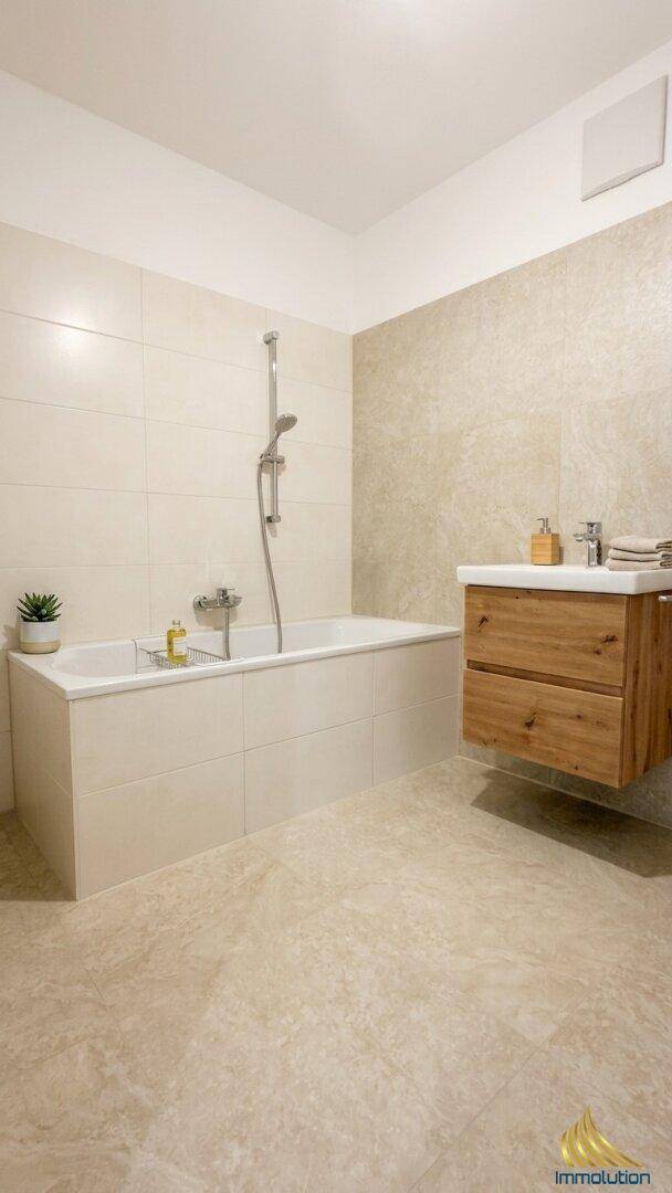 Modernes Badezimmer mit heller Fliesenverkleidung, Badewanne und einem schwebenden Waschtisch.