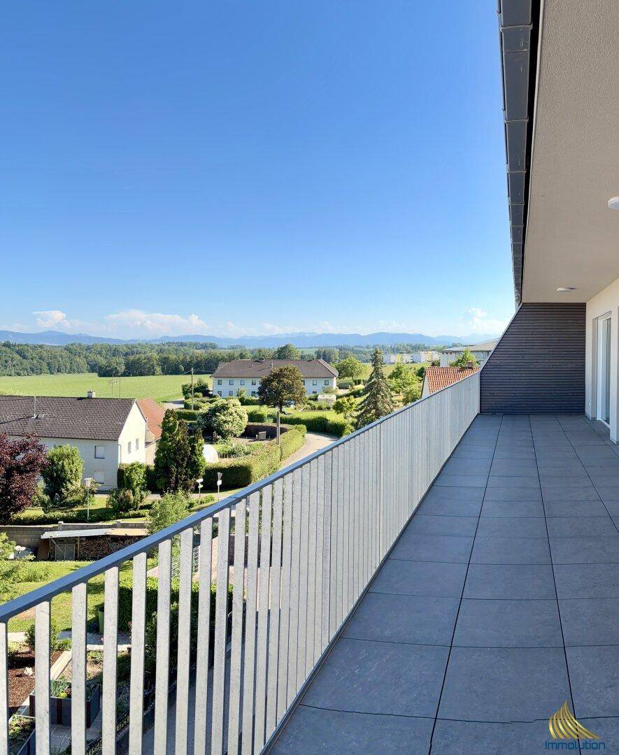 Langer Balkon mit Fliesenboden und weitem Blick über die grüne Landschaft.