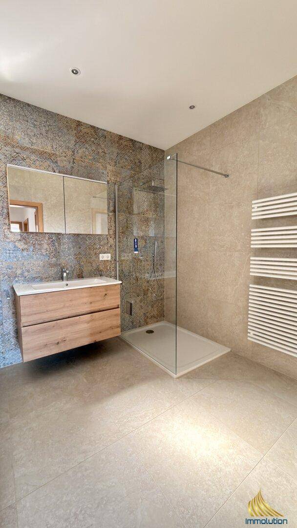 Modernes Badezimmer mit ebenerdiger Dusche, Holzwaschtisch und beheiztem Handtuchhalter.