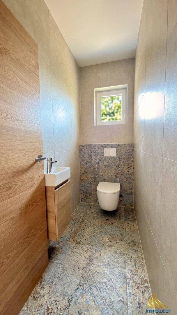 Modernes Gäste-WC mit Wand-WC, kleinem Waschbecken und Fenster.