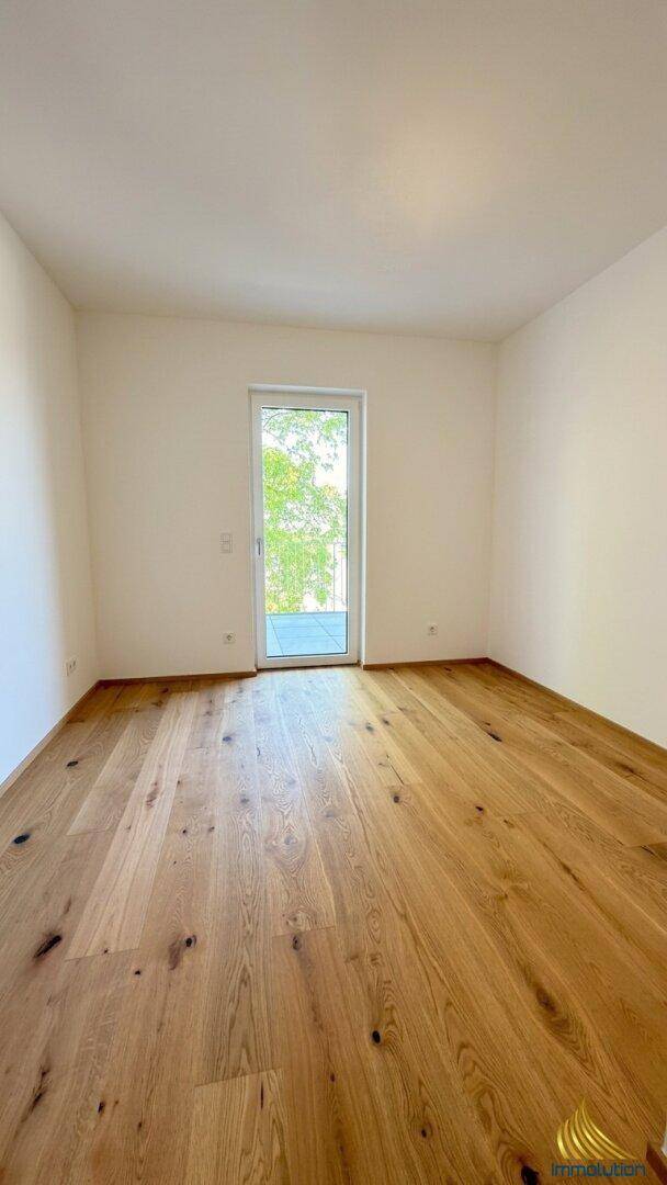 Schlafzimmer mit Holzboden und Zugang zu einem französischen Balkon oder kleiner Terrasse.