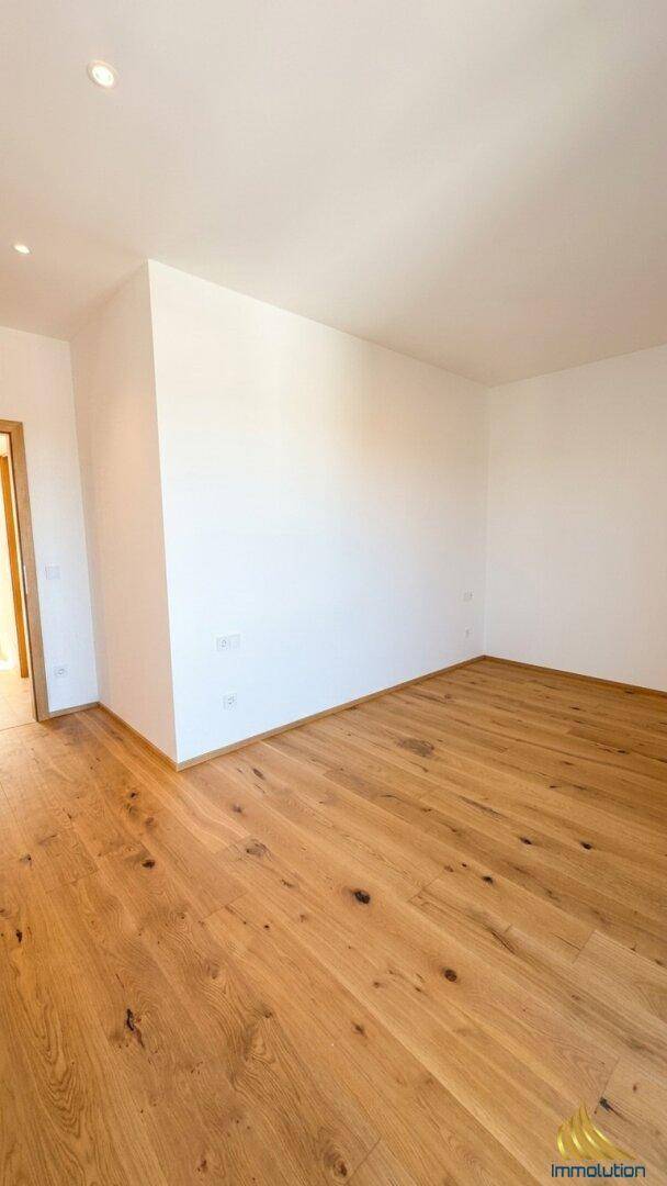 Helles Schlafzimmer mit Holzboden und weißen Wänden, ideal für Ruhe und Entspannung.
