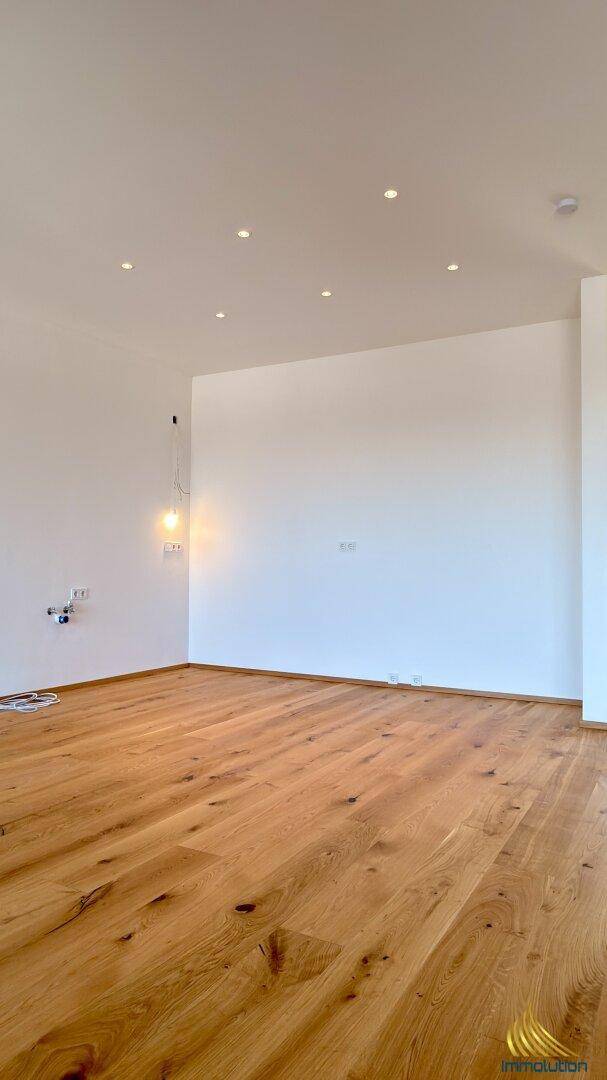Heller Raum mit elegantem Holzdielenboden und modernen Einbaustrahlern in der Decke.