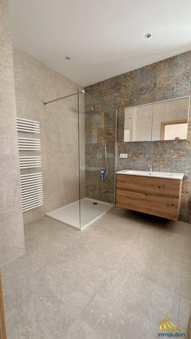 Modernes Badezimmer mit ebenerdiger Dusche, stilvollem Waschtisch und beheiztem Handtuchhalter.