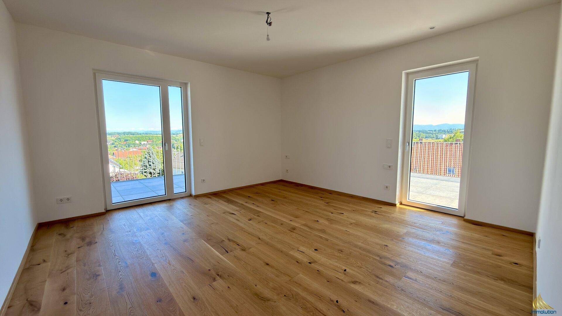Geräumiger, heller Raum mit Holzdielenboden und zwei Zugängen zu Außenbereichen.