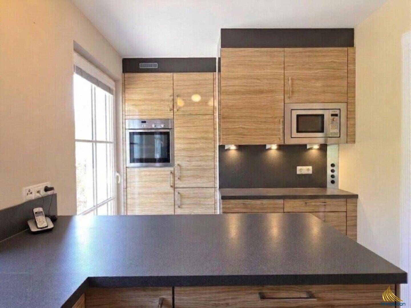 Funktionale Küche mit integriertem Backofen und Mikrowelle, sowie viel Stauraum.