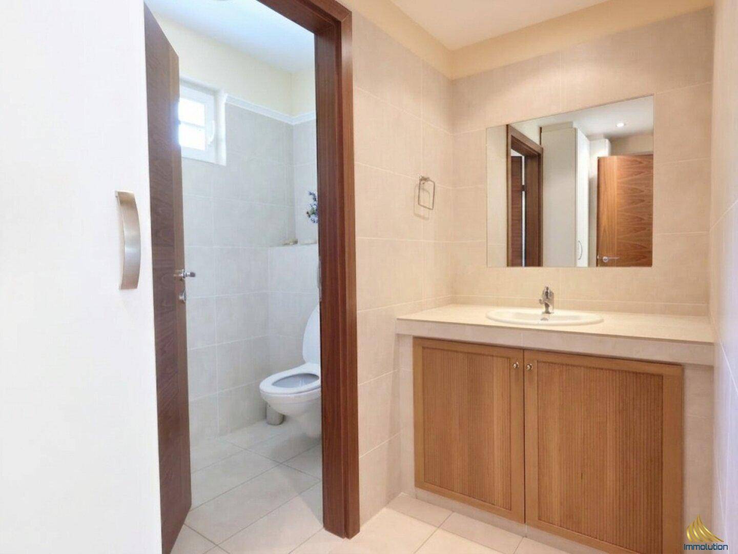 Helles Gäste-WC mit beigen Fliesen, Einzelwaschbecken und Holzunterschrank.