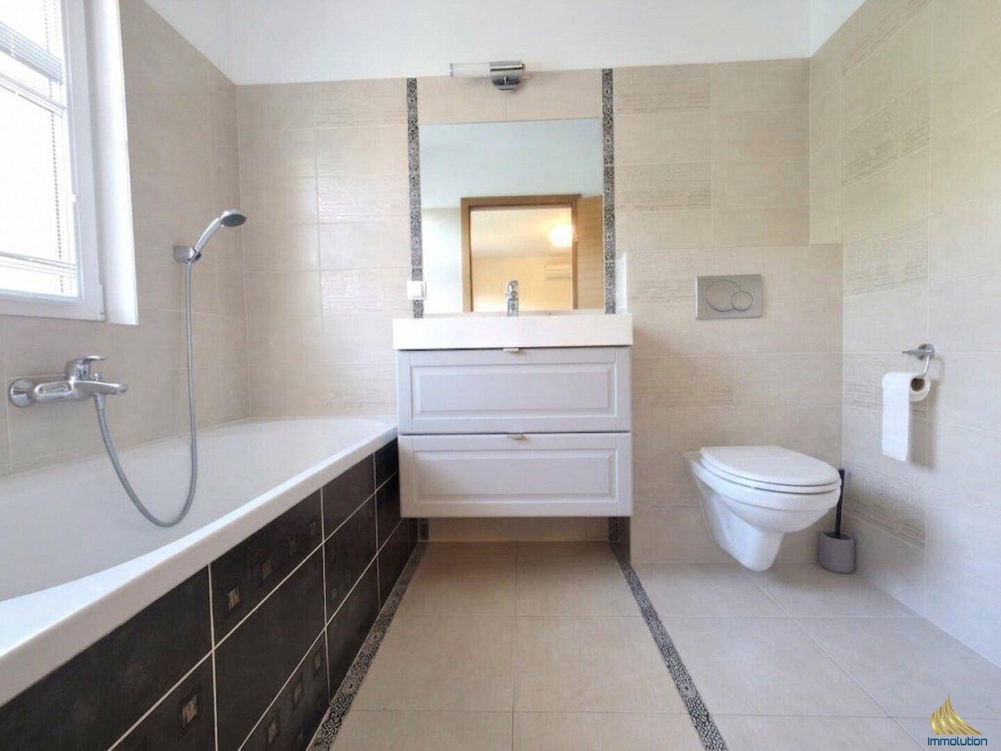 Modernes Badezimmer mit Badewanne, wandhängendem WC und Einzelwaschbecken.