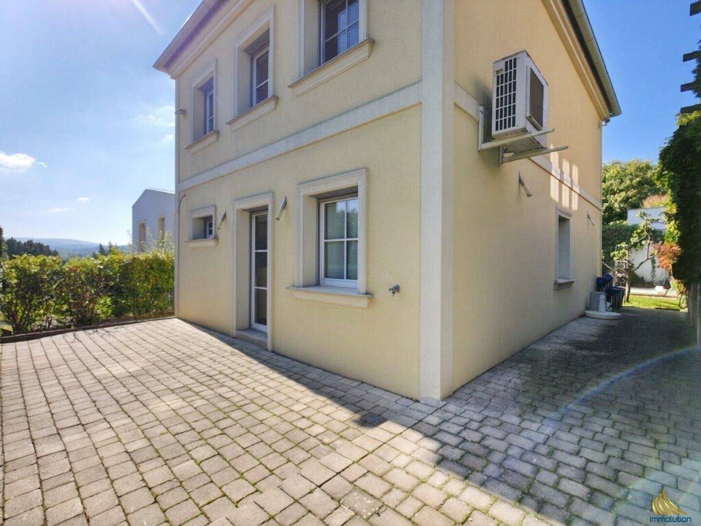 Seitenansicht des Hauses mit gepflastertem Bereich und Klimaanlage an der Fassade.